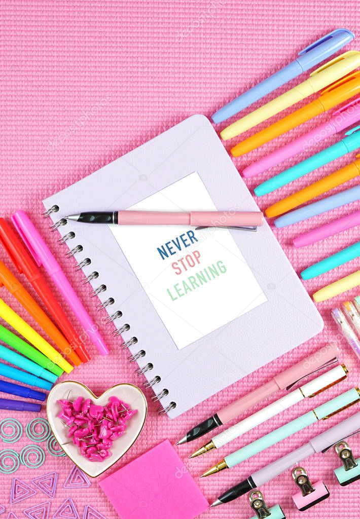 Back to school or workspace colorful stationery overhead on pink background.