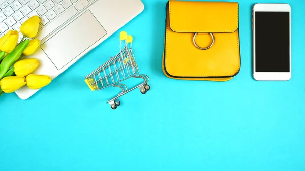 On-line shopping concept flatlay with shopping cart and accessories.
