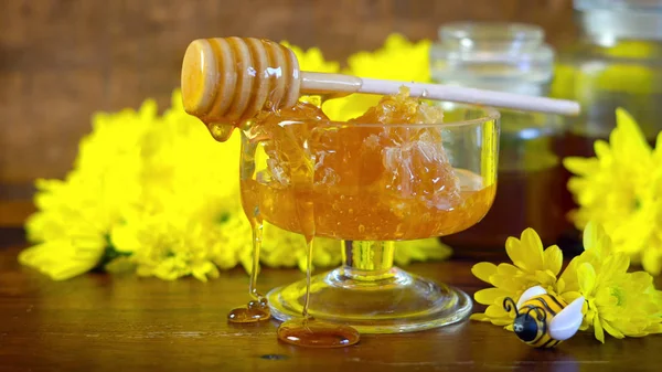 Rohe Wabe mit flüssigem Honig in Glasschale mit Servierlöffel. — Stockfoto