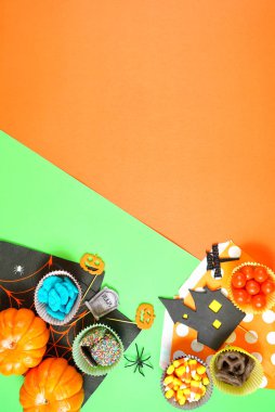 Halloween şeker ve kağıt düz parlak modern turuncu ve yeşil arka plan üzerinde yatıyordu.