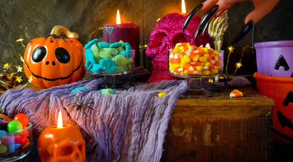 Tavolo da festa di Halloween con caramelle, zucche e candele scheletriche . — Foto Stock