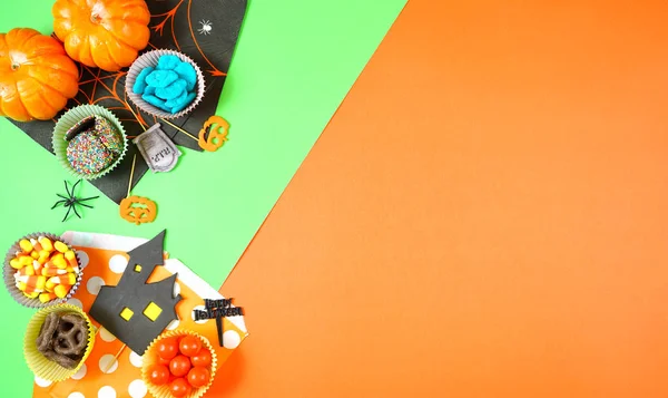 Halloween candy and paper flat lay on bright modern orange and green background. — Stock Photo, Image