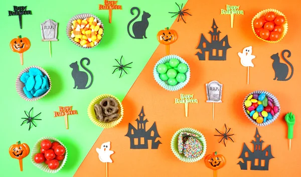 Halloween candy and paper flat lay on bright modern orange and green background. — Stock Photo, Image