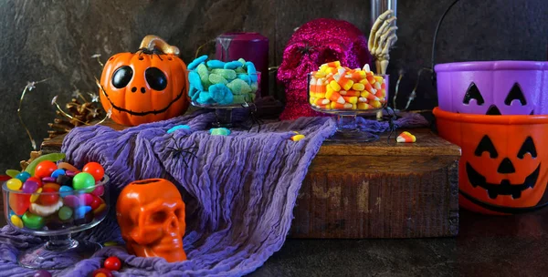 Halloween party table with candy, pumpkins and skeleton candles. — Stock Photo, Image