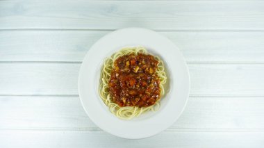 Spagetti bolognese domates sosu ve bir ahşap zemin masaya bir tabak beyaz et, metniniz için kopya alanı görünümüyle Top.