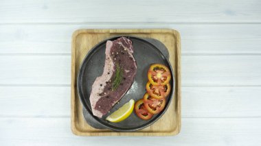 Taze çiğ Striploin sığır eti biftek tavada Beyaz ahşap zemin arka plan sahne dekorasyon domates, limon, siyah biber, Top, metniniz için kopya alanı görünümüyle.