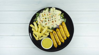 Kızarmış sosis biftek ve kızarmış siyah beyaz ahşap zemin arka plan sahne dekorasyon yeşil salata, mor karnabahar ve mayonez sos ile çanak, Top, metniniz için kopya alanı görünümüyle patates.