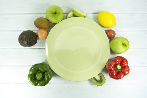 Salad Healthy food Green dish is empty on wood floor background props decoration kiwi, tomatoes, apple, avocado, Red chilli, Green pepper , lemon , lettuce, vitamin snack on white wooden background top view.