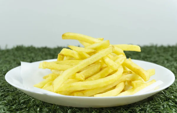 French Fries in a white dish on green grass on background.