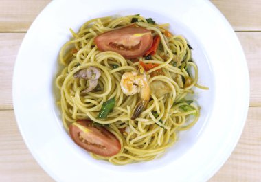Ahşap masada beyaz bir tabak spagetti baharatlı deniz ürünleri, gıda kavramı, Kapat