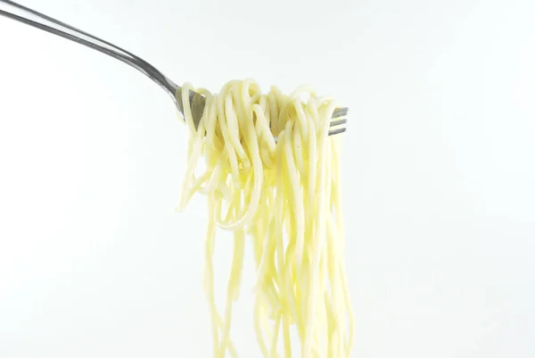 白い背景に生の黄色のスパゲッティのフォークを閉じます イタリアのパスタを調理するための食材 食品のコンセプト トップビュー コピースペース — ストック写真