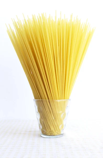 黄色いテーブルクロスの上のグラスに生のスパゲッティ イタリアンパスタを調理するための材料 食品コンセプト — ストック写真