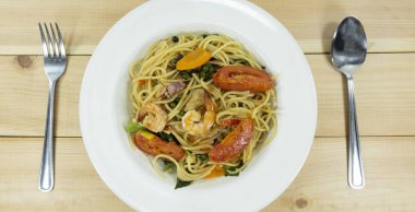 Ahşap arka planda beyaz bir tabakta spagetti deniz ürünleri.