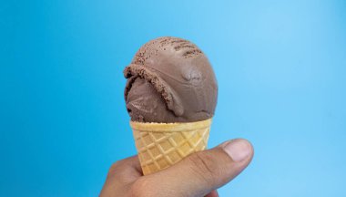 Adamın elinde dondurma külahı çikolata aromalı mavi arka planda, Front View Food konsepti.