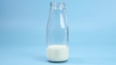 Hareket animasyonunu durdur Mavi arka planda taze süt şişesi sapı, Yakın plan yiyecek konsepti.