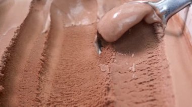 Yakın plan dondurma kepçeleme konteynırdan çikolata aromalı kaşık, tasarım için boş yiyecek konsepti.