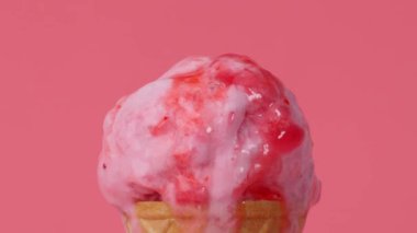 Time Lapse Dondurması 'nı kapayın. Pembe arka planda waffle külahında çilek kepçesi..