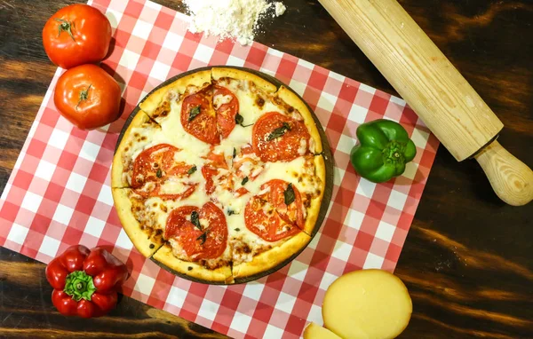 Tahta bir masada ev yapımı pizza margherita.