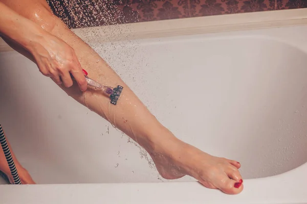 妇女在浴室里刮腿的特写镜头 图库照片
