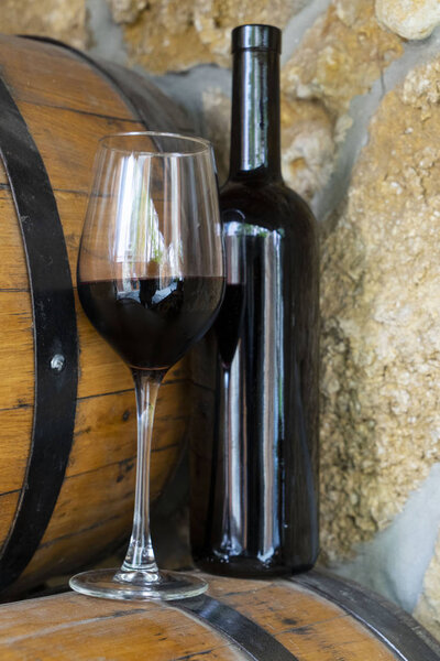     Wine and wine glass on the background of barrels and walls.