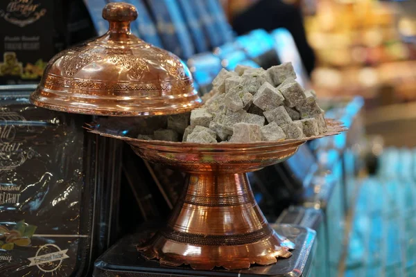 Bakır bir vazoda Türk lokumu. Arka planda şekerli kutuların kapağı var.