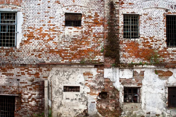 Prison in Siberia  an abandoned unrepaired building of the old prison in Tobolsk (Russia): red brick texture on a white wall, Windows in bars