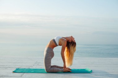 Denizde yoga yapan kadın.