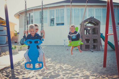 Üç kardeş bahçesinde bir salıncak üzerinde eğleniyor