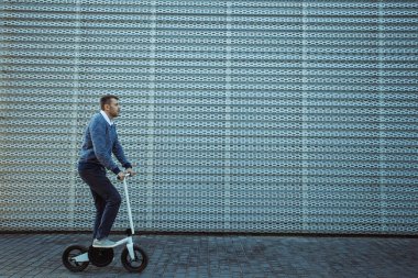 Adam güzel dolgu üzerinde sürme sırasında tekme scooter iterek yan görünüm 