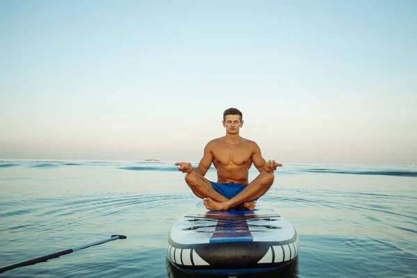 Genç ve sportif adam relax biraz Sup tahta üzerinde günbatımında alıyorum.