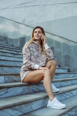 Genç bir kız üzerinde siting adımlar ve telefonla konuşuyor