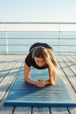 Genç kadın plajda yoga yapıyor.
