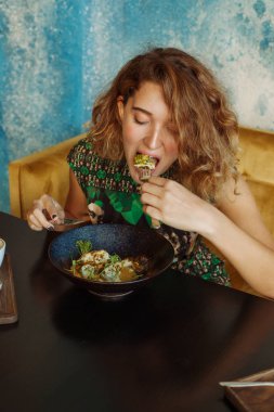 Bir kafede kahvaltı yapan genç bir kadın.