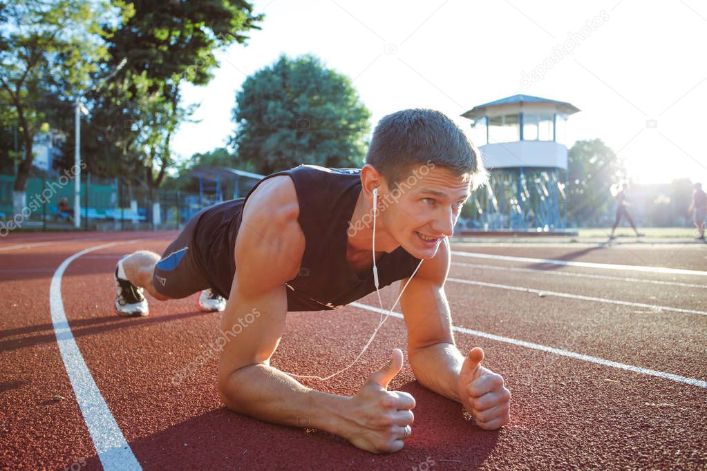 Young male jogger athlete training and doing workout outdoors in city