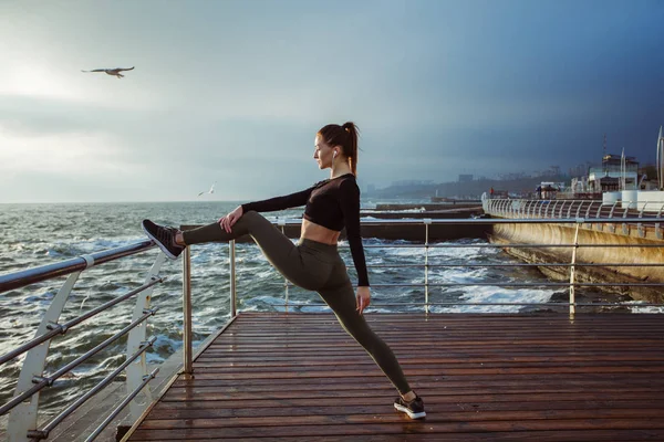 Fitness modeli atlet kız onun hamstrings, sırt ve bacak Germe kadar sıcak