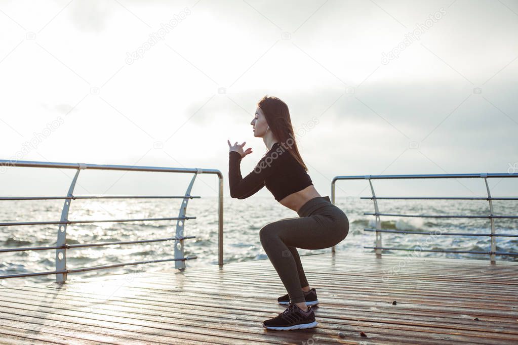 Girl in sportswear doing morning exercises on the beach