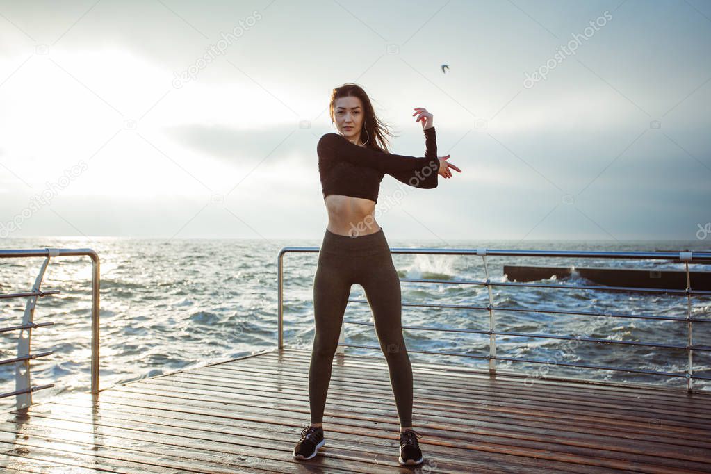 Girl in sportswear doing morning exercises on the beach