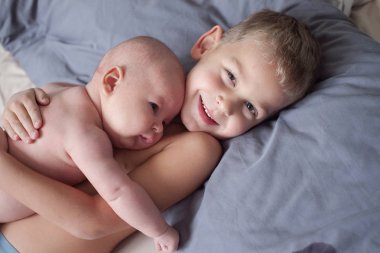 Beyaz bodysuits yatakta birlikte evde yatarken şirin küçük kardeşler