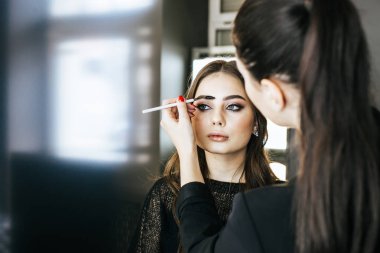 Kırpma elinde çekici genç esmer modeli Studio işyerinde sanatçı makyaj