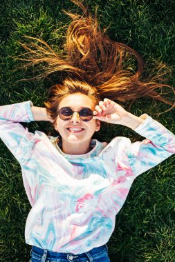 Beyaz beyazlı kız yeşil çimenlerin üzerinde dinleniyor. Güzel kız sahada yatıyor