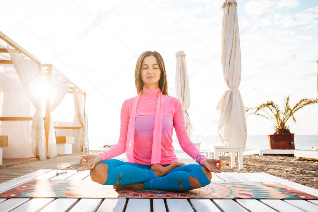 Young woman meditating in nature by the river. Natural light. Backlit by the sun