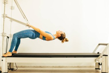 Bir Cadillac veya trapeze masa kullanarak Pilates Egzersiz yapan kadın