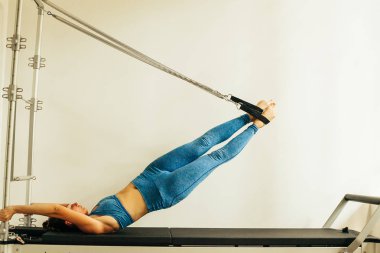 Bir Cadillac veya trapeze masa kullanarak Pilates Egzersiz yapan kadın