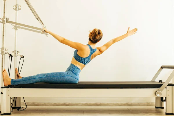 Bir Cadillac veya trapeze masa kullanarak Pilates Egzersiz yapan kadın