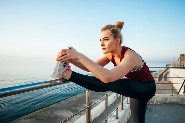 ビーチでストレッチ ランニングの準備をする魅力的なスポーツウーマン — ストック写真