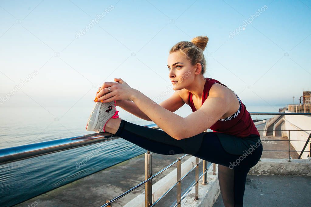 An attractive sportswoman stretching on the beach, preparing for running