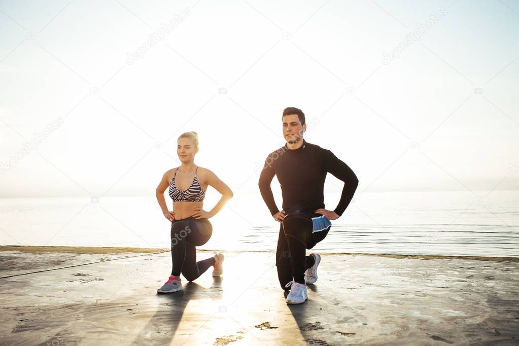 Fitness, sport, friendship and lifestyle concept - couple exercising at the beach