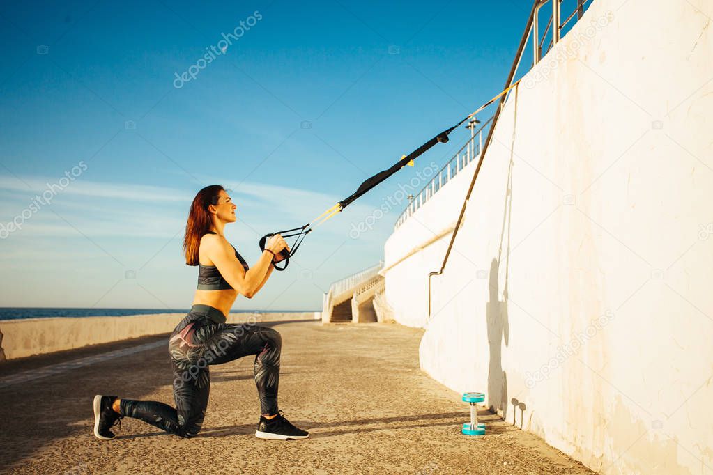 young sporty woman doing TRX in the outdoor