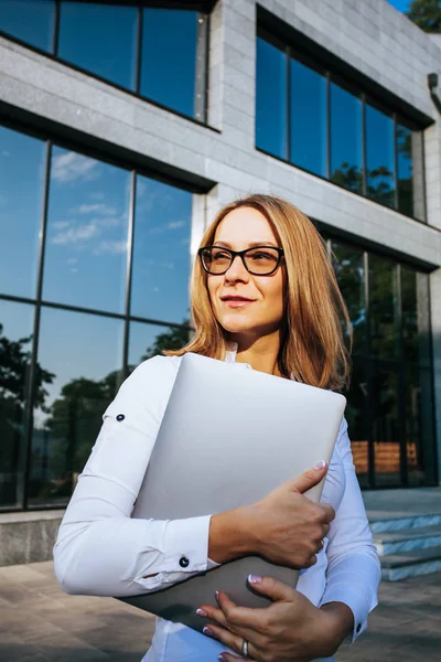 Young business woman with laptop at the office building