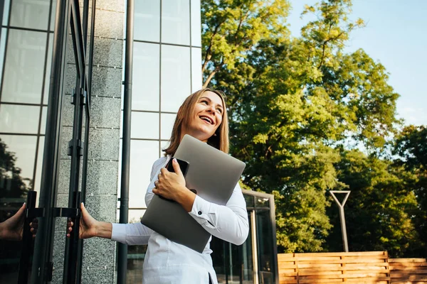 Young business woman with laptop at the office building